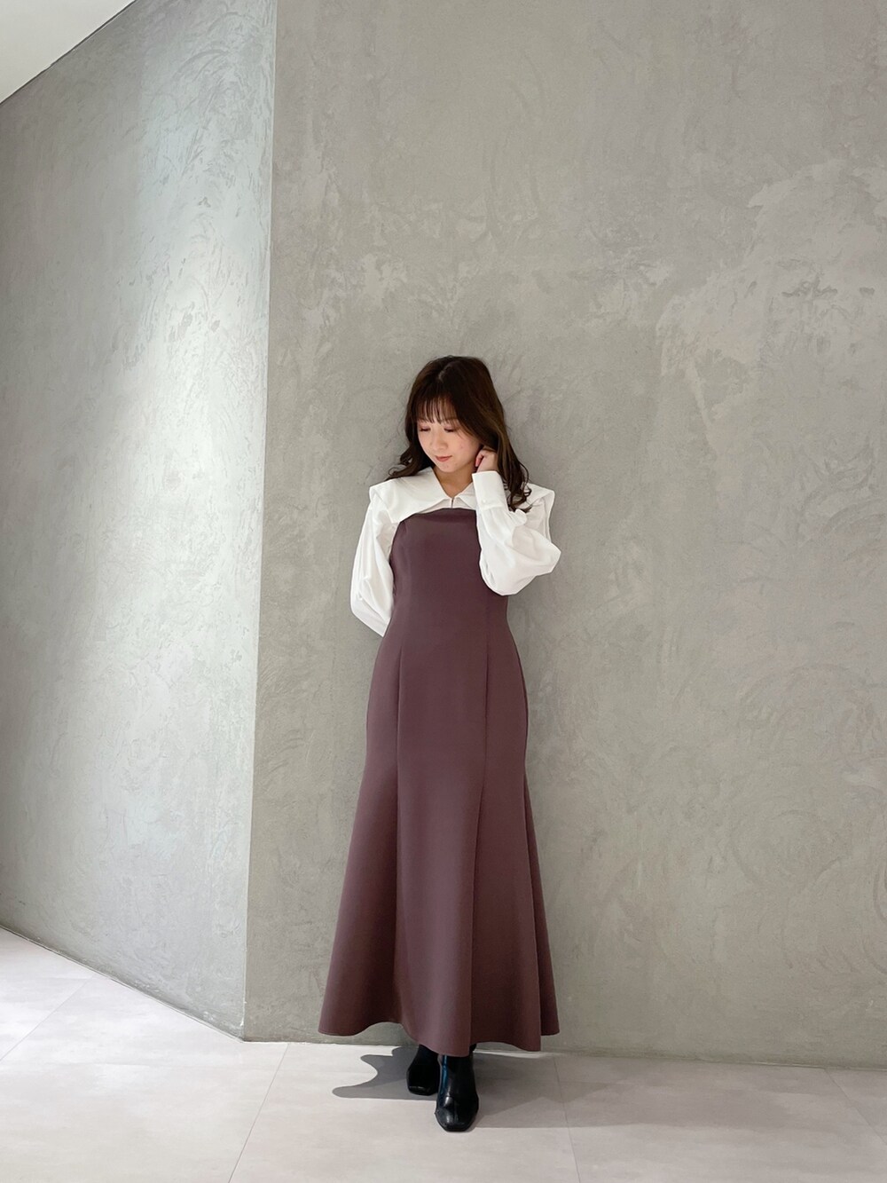 パープル系のワンピース、ブラック系のブーツ、ホワイト系のトレンチコートを着用したレディースの冬コーディネートの3枚目の写真