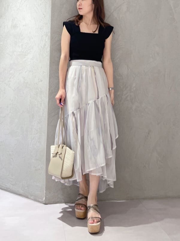 ピンク系のスカート、ブラック系のニット/セーター、ベージュ系のトートバッグを着用したレディースの夏コーディネートの5枚目の写真