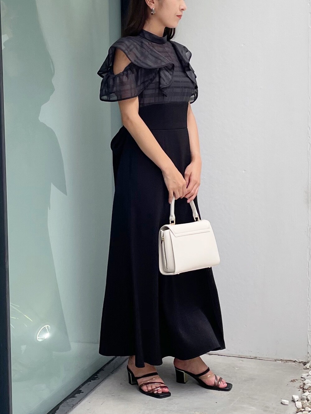 ブラック系のワンピース、ブラック系のサンダル、ホワイト系のショルダーバッグを着用したレディースの夏コーディネートの7枚目の写真
