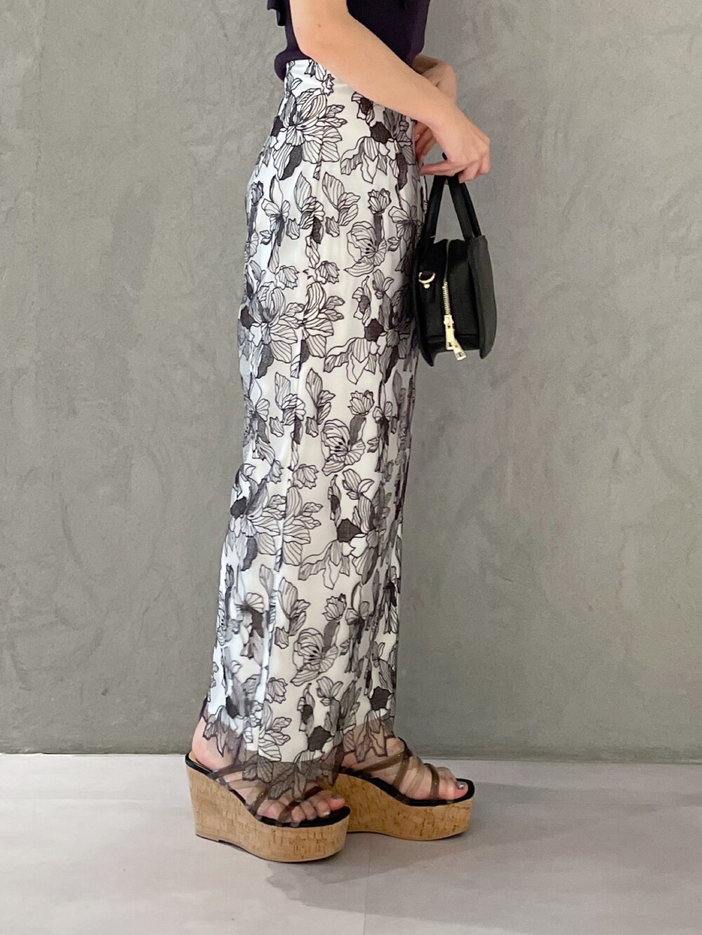 ブラック系のハンドバッグ、ブラック系のサンダル、グレー系のニット/セーターを着用したレディースの春コーディネートの3枚目の写真