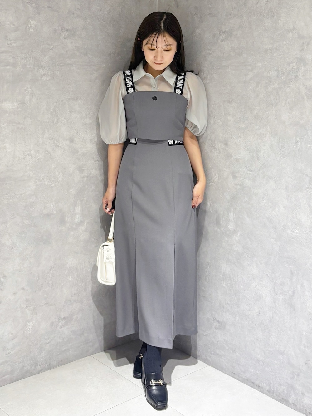 グレー系のスカート、ブラック系のブーツ、ホワイト系のハンドバッグを着用したレディースの春コーディネートの6枚目の写真