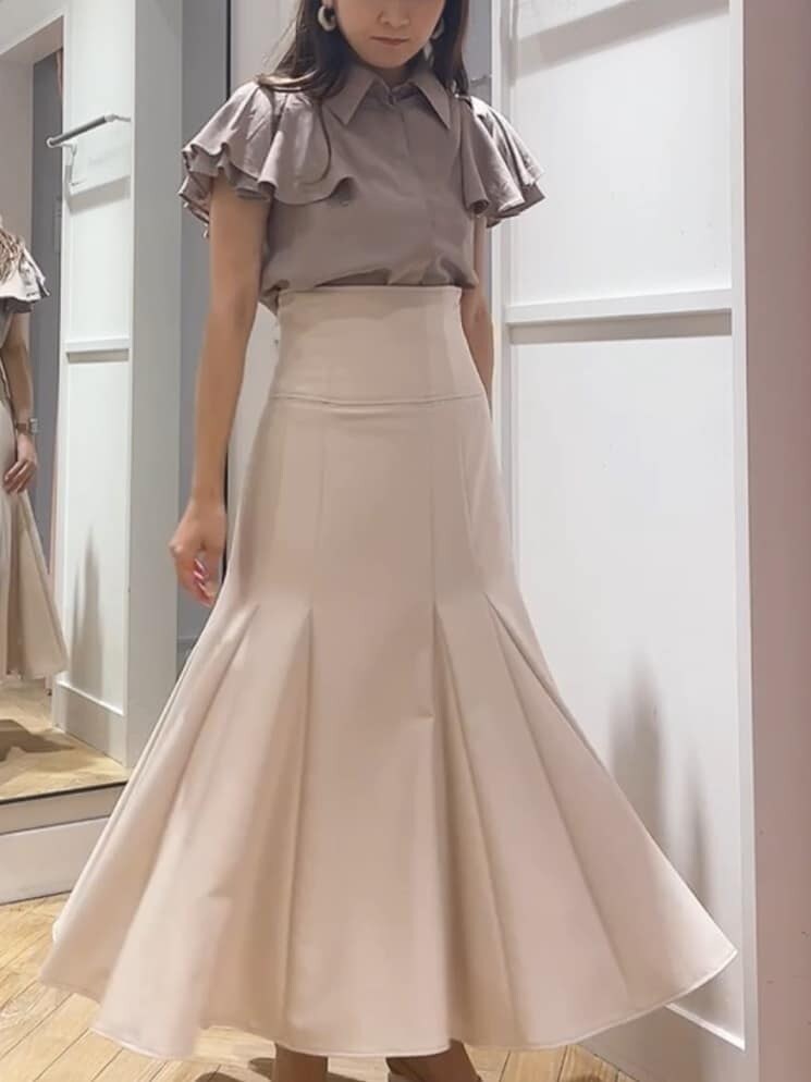 ベージュ系のシャツ/ブラウス、ピンク系のスカート、ベージュ系のサンダルを着用したレディースの夏コーディネートの2枚目の写真