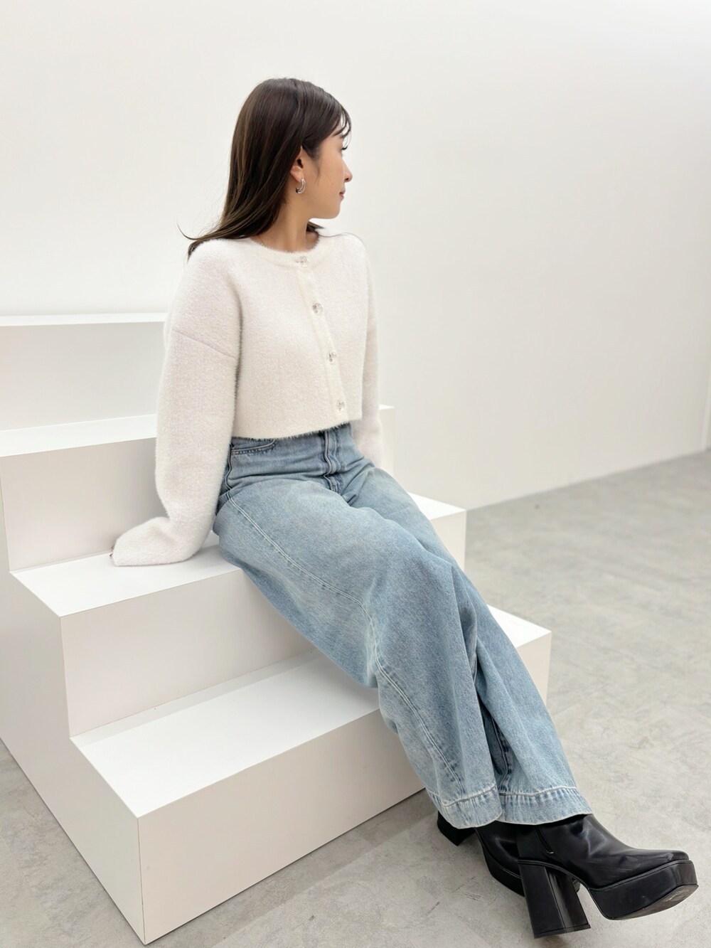 ブルー系のデニムパンツ、ブラック系のブーツ、ホワイト系のカーディガン/ボレロを着用したレディースの秋コーディネートの4枚目の写真