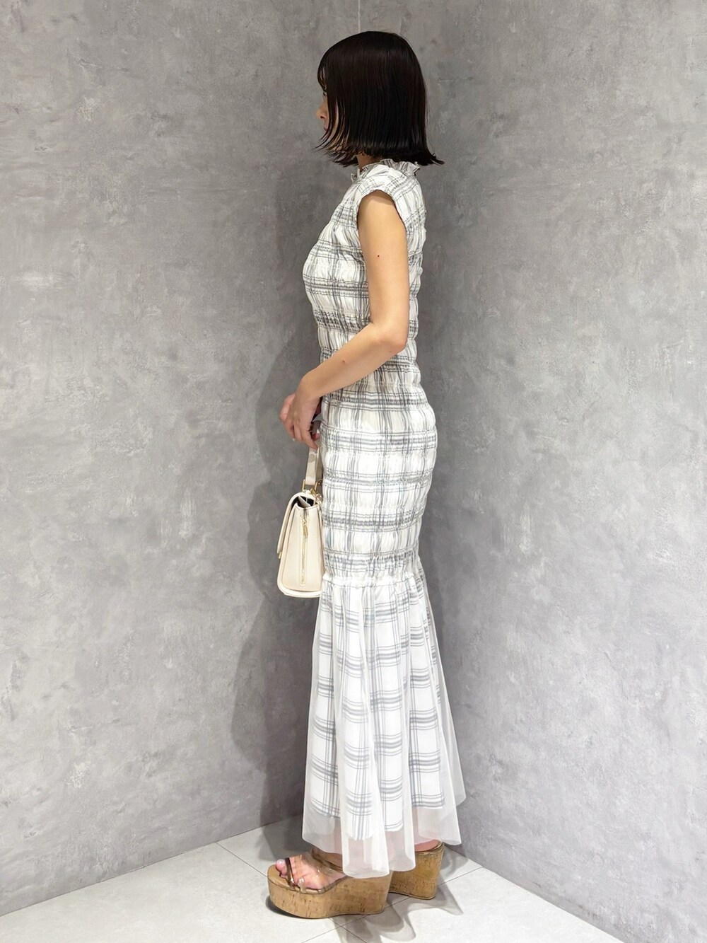 ホワイト系のワンピース、ブラウン系のサンダル、ホワイト系のハンドバッグを着用したレディースの夏コーディネートの2枚目の写真