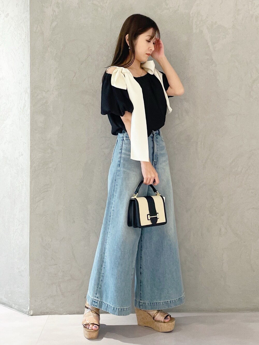 ブラウン系のサンダル、ブラック系のハンドバッグ、ブルー系のデニムパンツを着用したレディースの春コーディネートの4枚目の写真