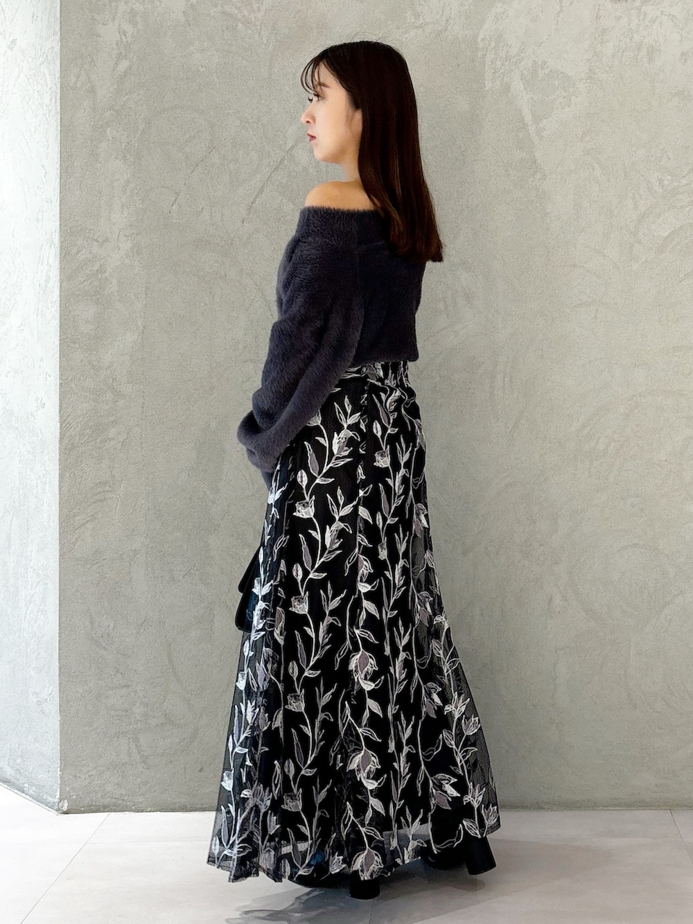 グレー系のスカート、ブラック系のブーツ、ブラック系のショルダーバッグを着用したレディースの秋コーディネートの2枚目の写真