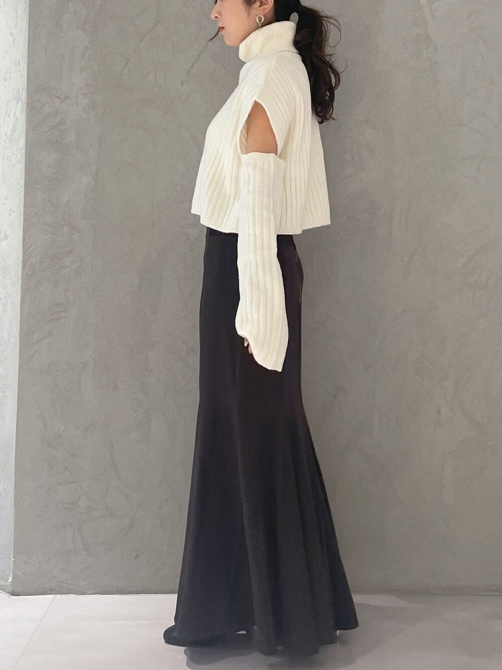 ブラウン系のスカート、ホワイト系のニット/セーターを着用したレディースの冬コーディネートの2枚目の写真