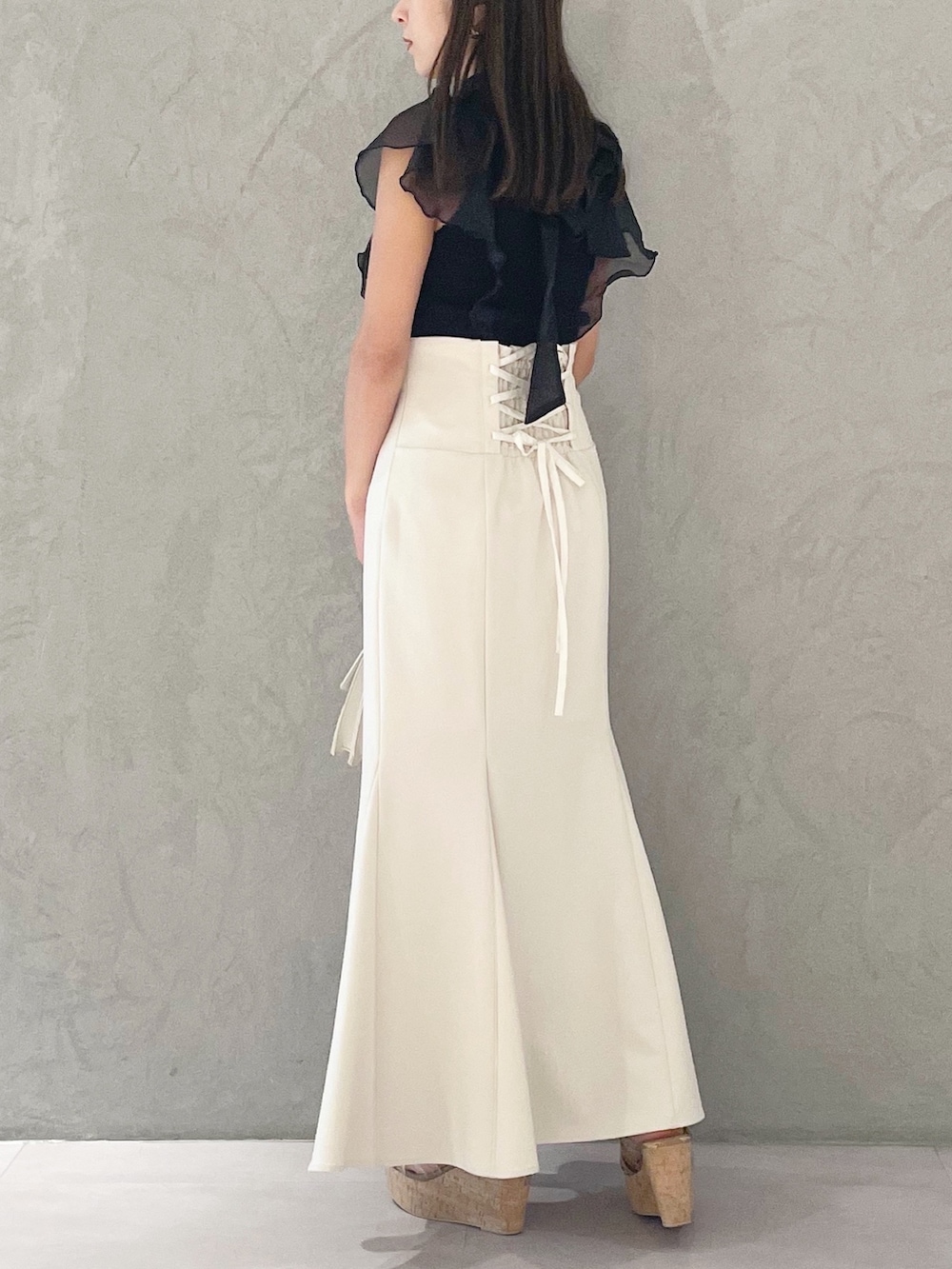 ブラック系のニット/セーター、ホワイト系のスカート、ブラウン系のサンダルを着用したレディースの夏コーディネートの4枚目の写真