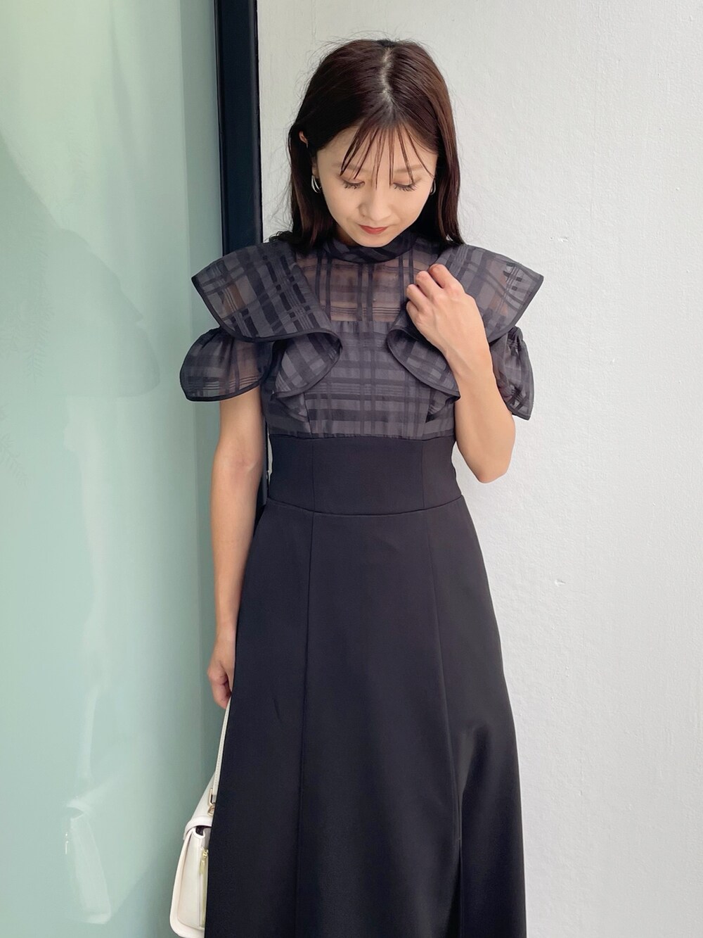 ブラック系のワンピース、ブラック系のサンダル、ホワイト系のショルダーバッグを着用したレディースの夏コーディネートの4枚目の写真