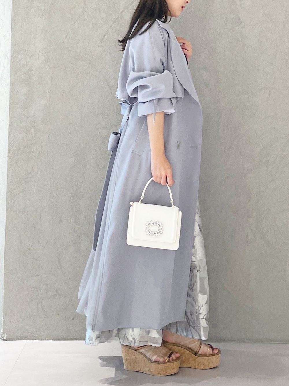 ブルー系のトレンチコート、ブラウン系のサンダル、ホワイト系のショルダーバッグを着用したレディースの春コーディネートの5枚目の写真