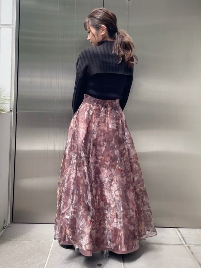 ブラウン系のスカート、ブラック系のニット/セーター、ブラック系のブーツを着用したレディースの秋コーディネートの4枚目の写真