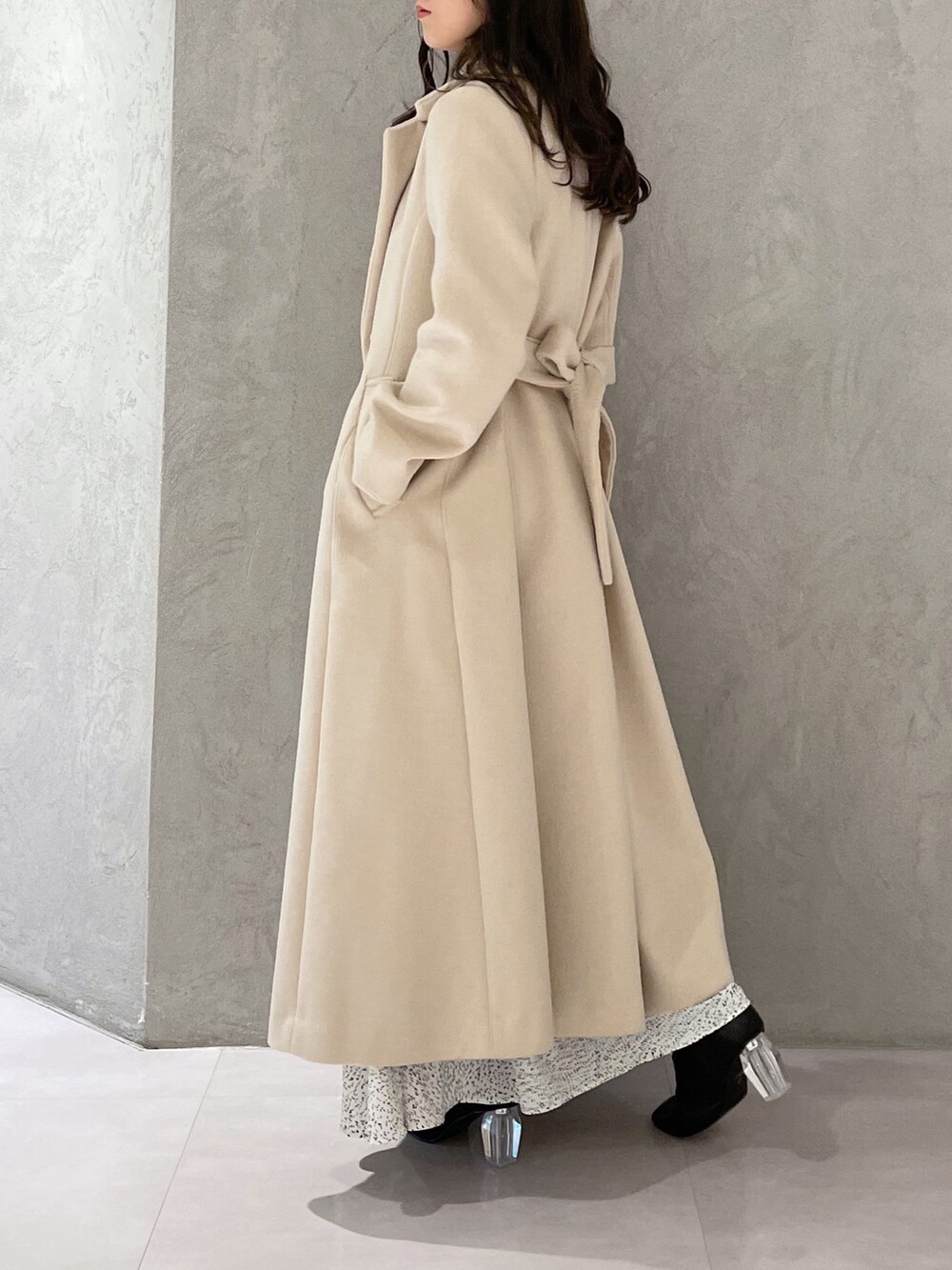 ホワイト系のワンピース、ベージュ系のチェスターコート、ブラック系のブーツを着用したレディースの秋コーディネートの3枚目の写真