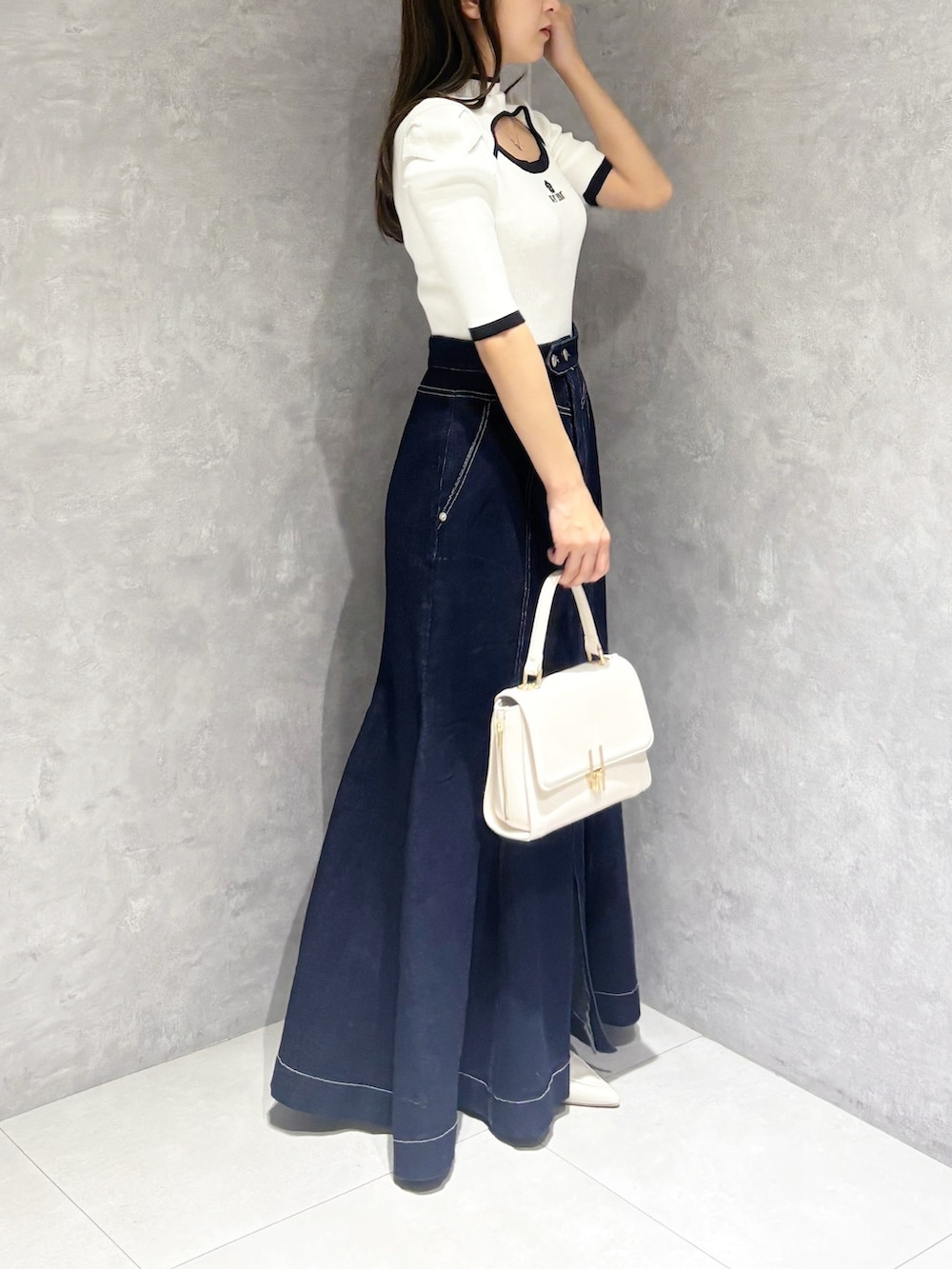 ブルー系のスカート、ホワイト系のパンプス、ホワイト系のハンドバッグを着用したレディースの春コーディネートの4枚目の写真