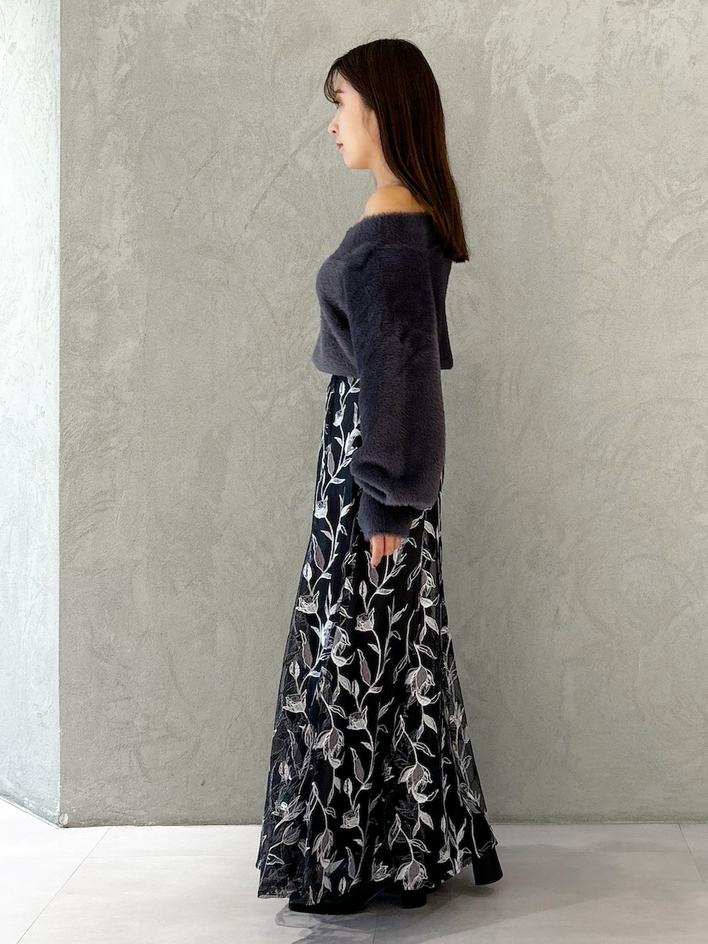 グレー系のスカート、ブラック系のブーツ、ブラック系のショルダーバッグを着用したレディースの秋コーディネートの8枚目の写真