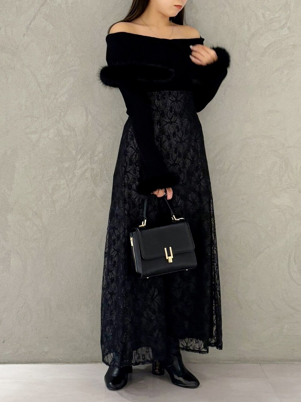 ブラック系のスカート、ブラック系のブーツ、ブラック系のショルダーバッグを着用したレディースの冬コーディネートの4枚目の写真