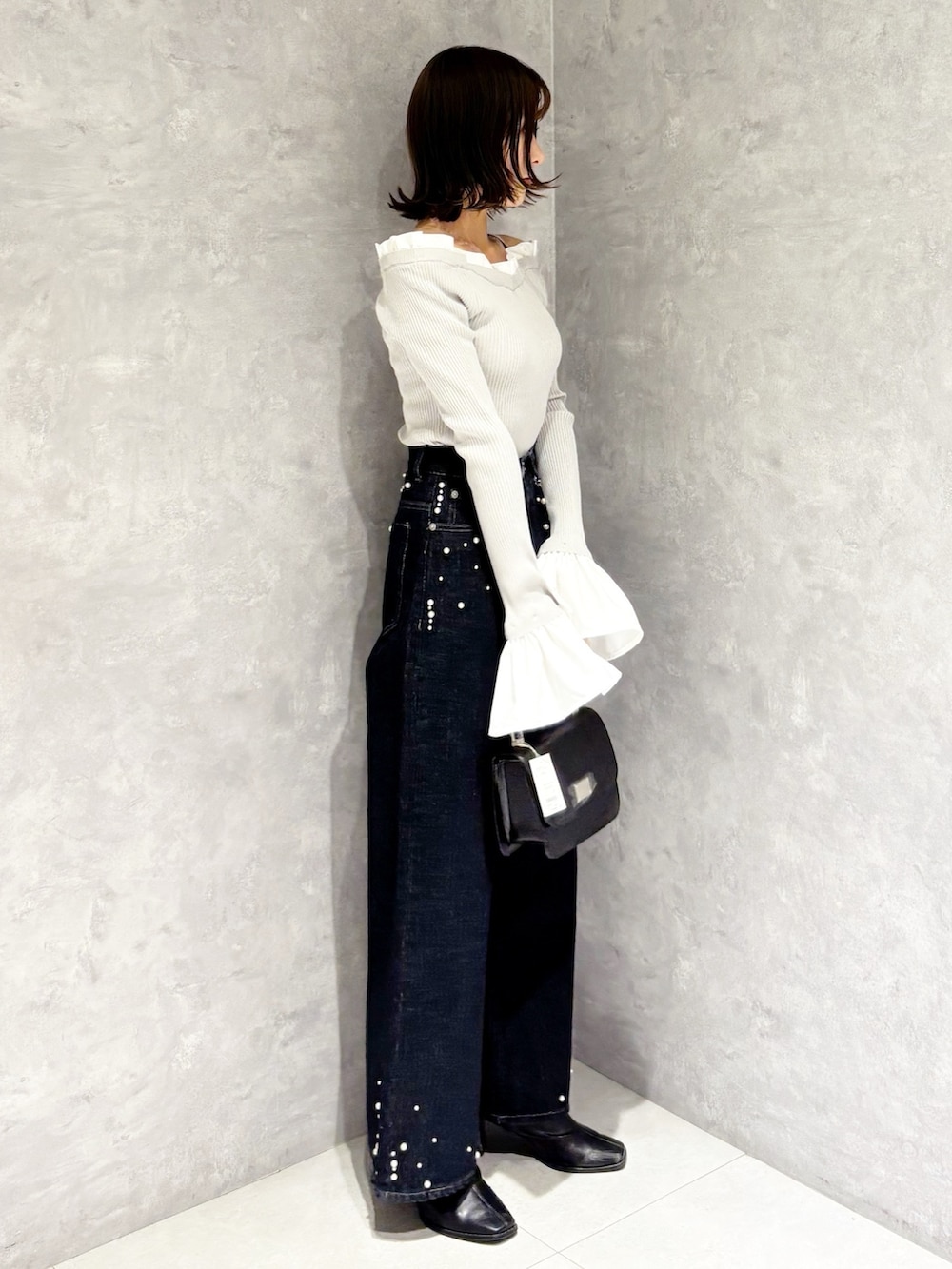 グレー系のニット/セーター、ブルー系のデニムパンツ、ブラック系のブーツを着用したレディースの秋コーディネートの2枚目の写真