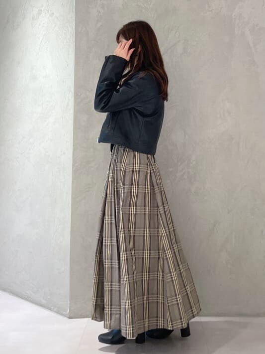 ブラック系のライダースジャケット、ブラック系のニット/セーター、ベージュ系のスカートを着用したレディースの秋コーディネートの3枚目の写真