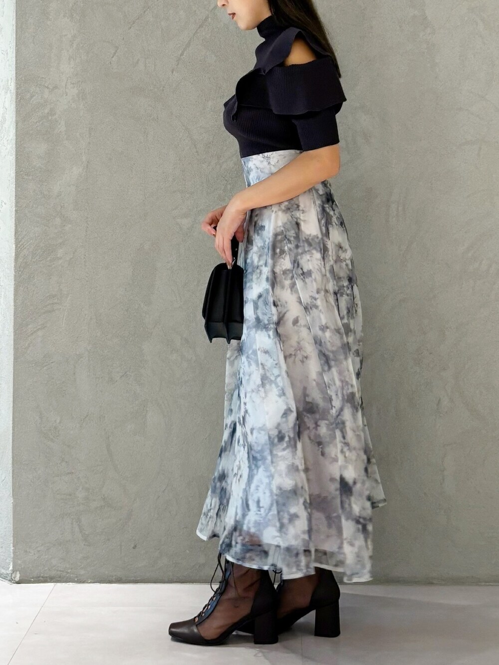 グレー系のスカート、ブラウン系のブーツ、ブラック系のショルダーバッグを着用したレディースの夏コーディネートの3枚目の写真