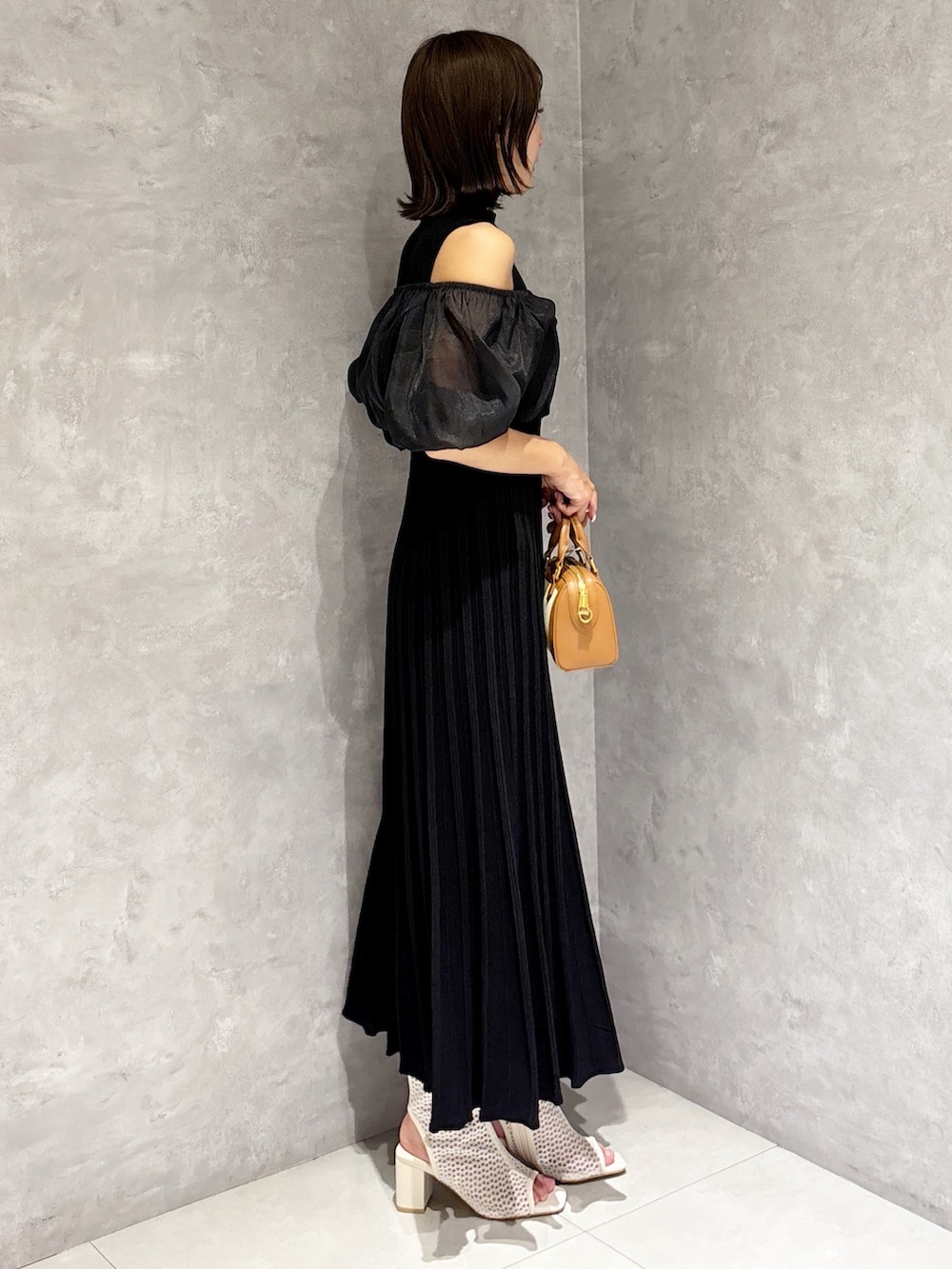 ブラウン系のハンドバッグ、ブラック系のワンピースを着用したレディースの春コーディネートの2枚目の写真