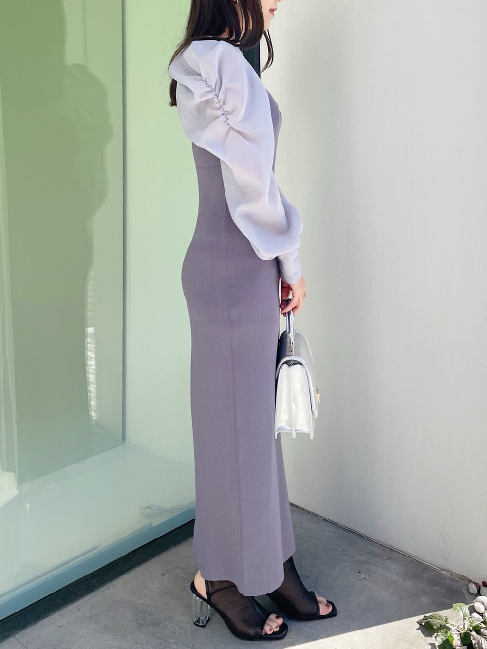 シルバー系のハンドバッグ、ブラック系のブーツ、ブルー系のワンピースを着用したレディースの春コーディネートの2枚目の写真