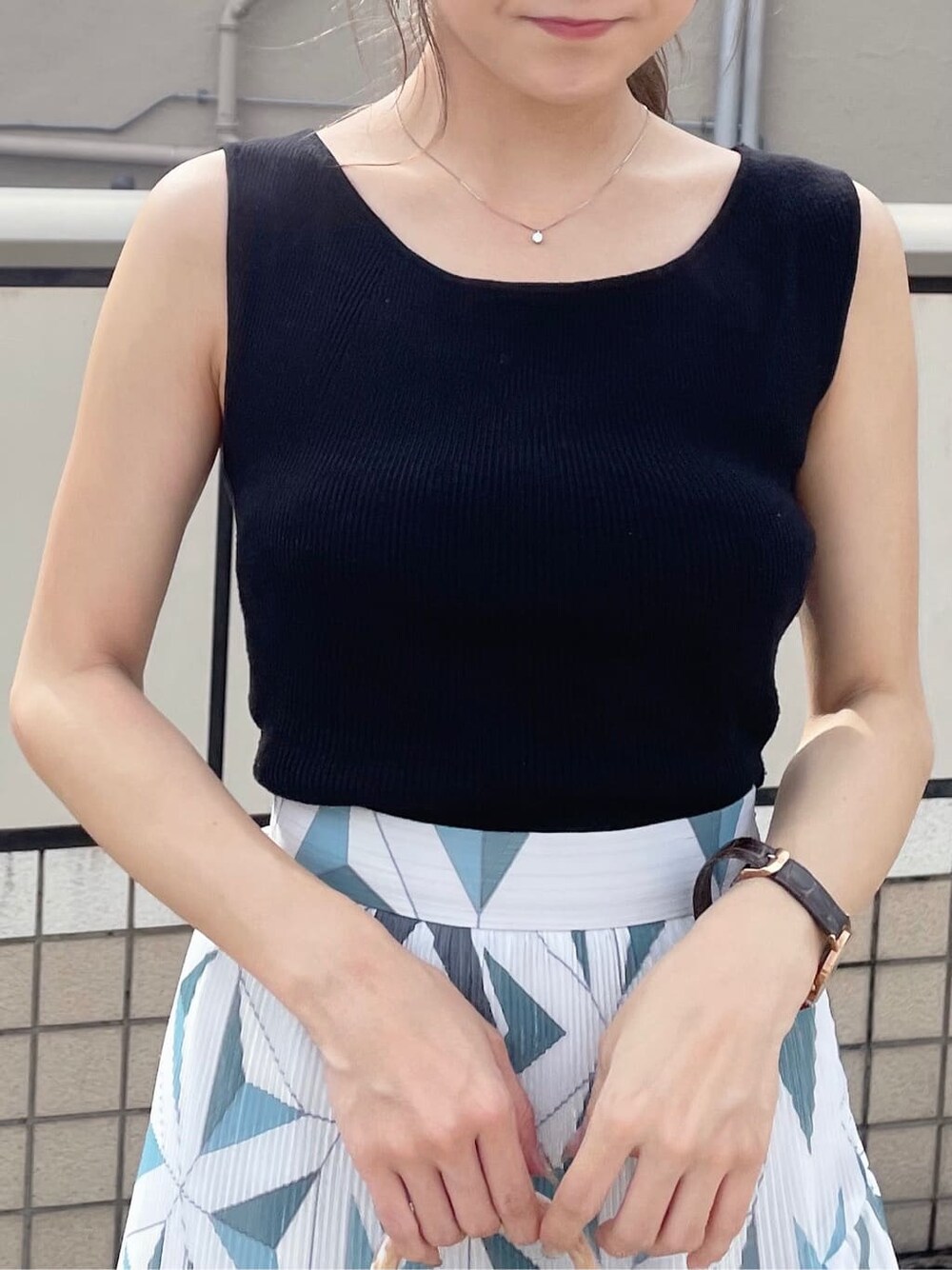 ブルー系のスカート、ホワイト系のハンドバッグ、ブラック系のニット/セーターを着用したレディースの夏コーディネートの5枚目の写真