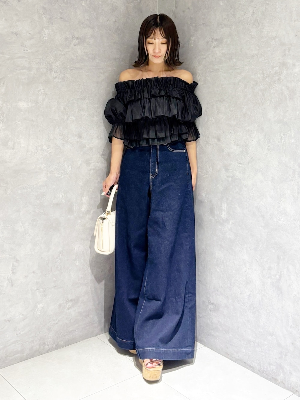 ブルー系のデニムパンツ、ブラウン系のサンダル、ホワイト系のハンドバッグを着用したレディースの夏コーディネートの7枚目の写真