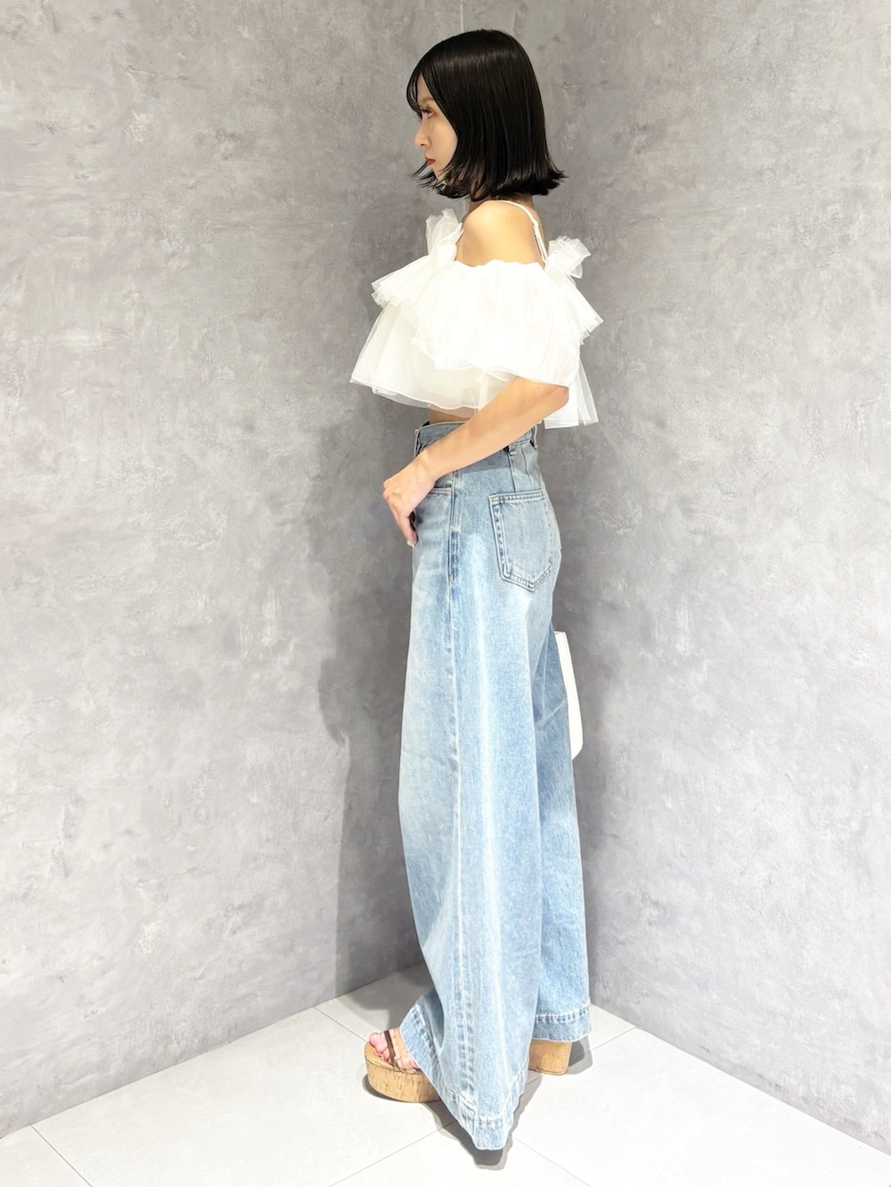 ブルー系のデニムパンツ、ブラウン系のサンダル、ホワイト系のトートバッグを着用したレディースの春コーディネートの3枚目の写真