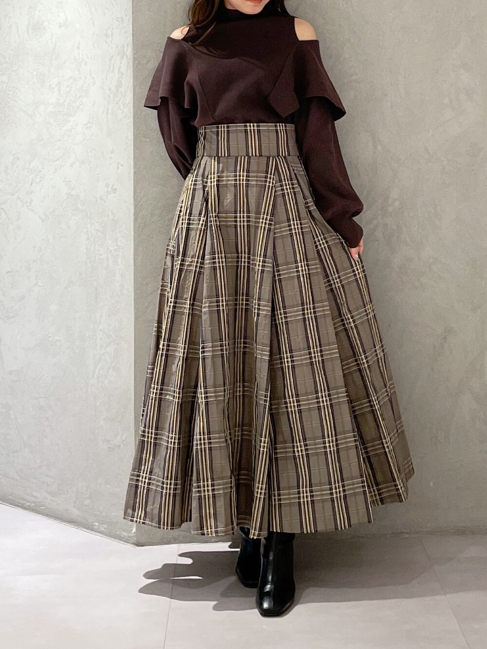 ベージュ系のスカート、ブラウン系のニット/セーター、ブラック系のブーツを着用したレディースの秋コーディネートの4枚目の写真