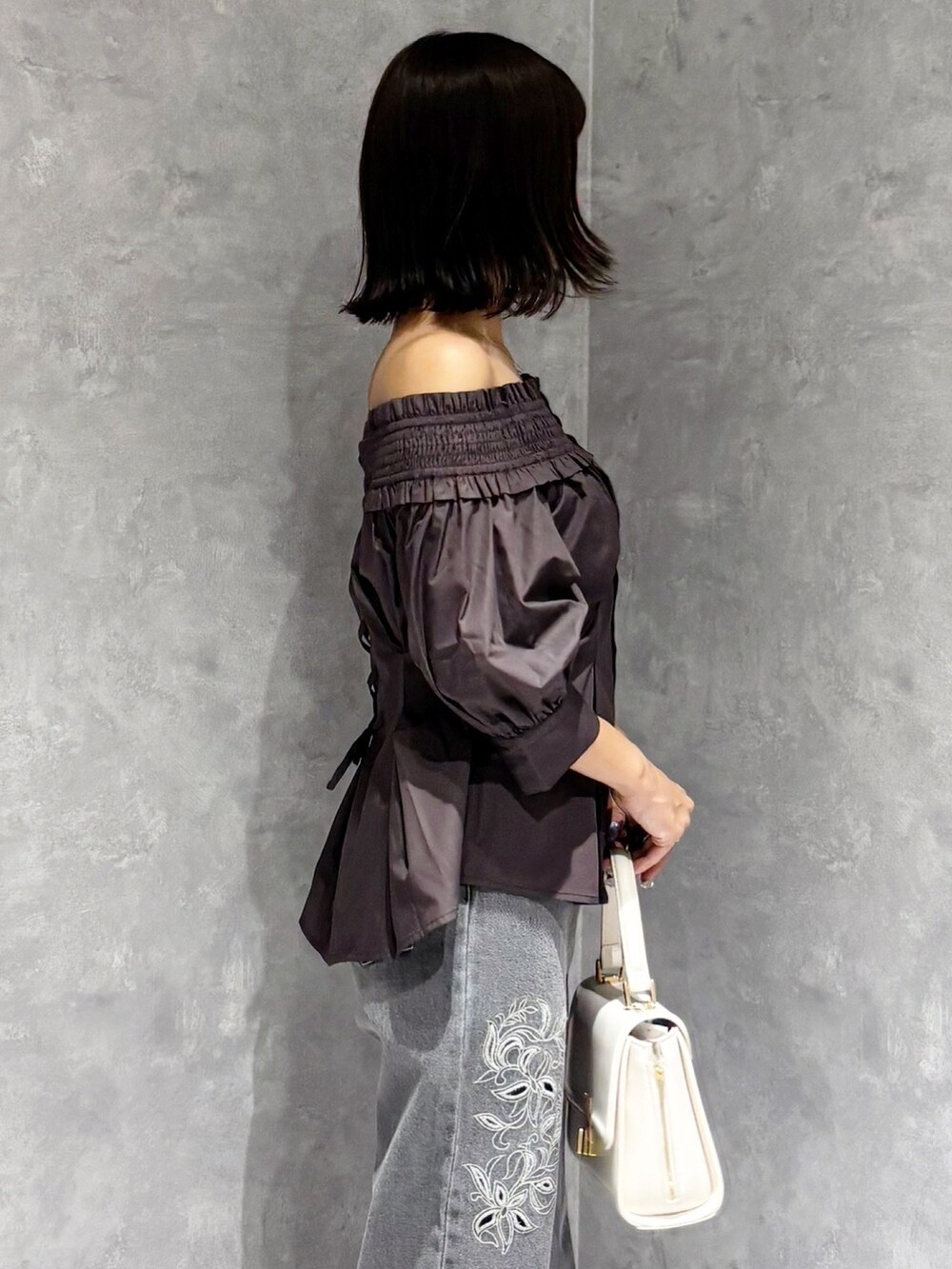 ホワイト系のハンドバッグ、ブラック系のパンプス、グレー系のデニムパンツを着用したレディースの夏コーディネートの3枚目の写真