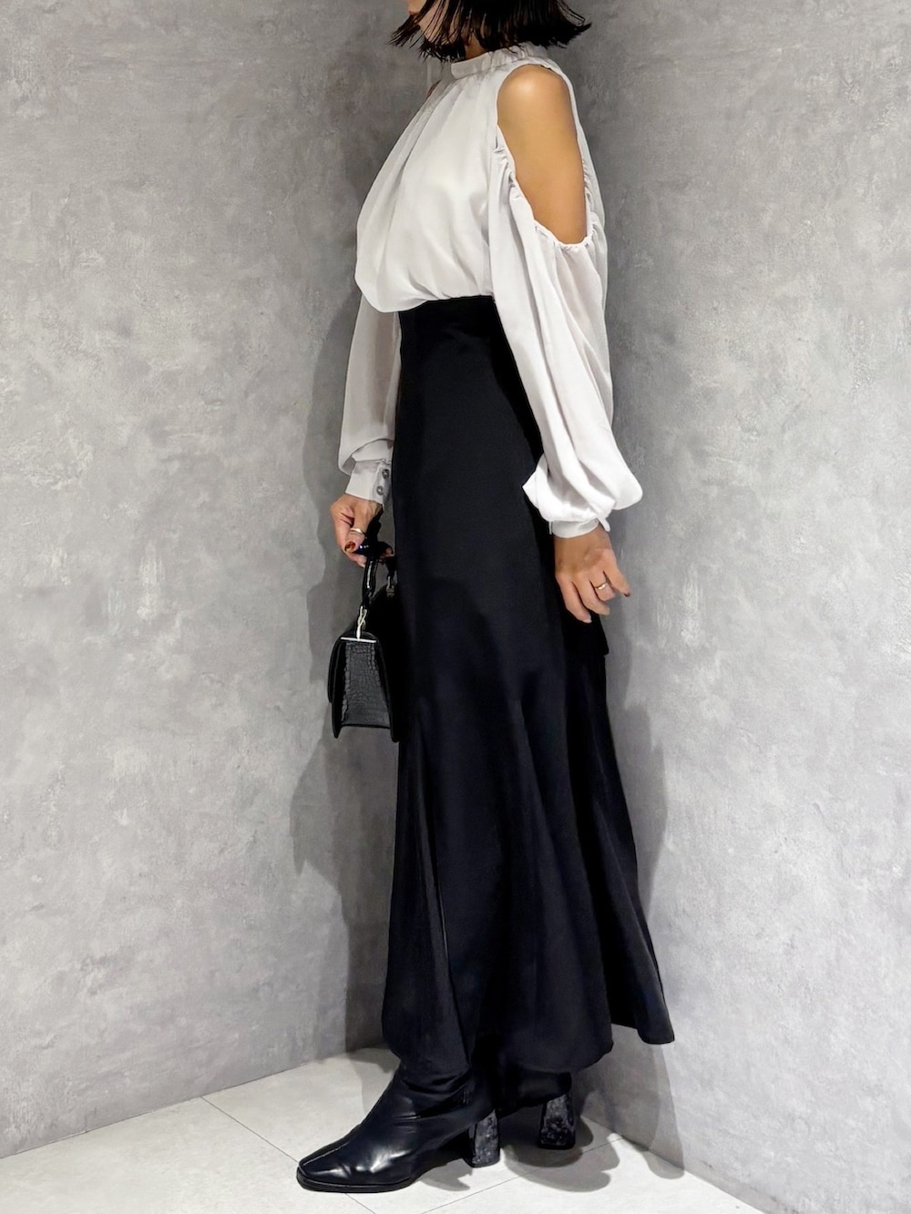 ブラック系のハンドバッグ、ブラック系のブーツ、ブラック系のスカートを着用したレディースの秋コーディネートの2枚目の写真