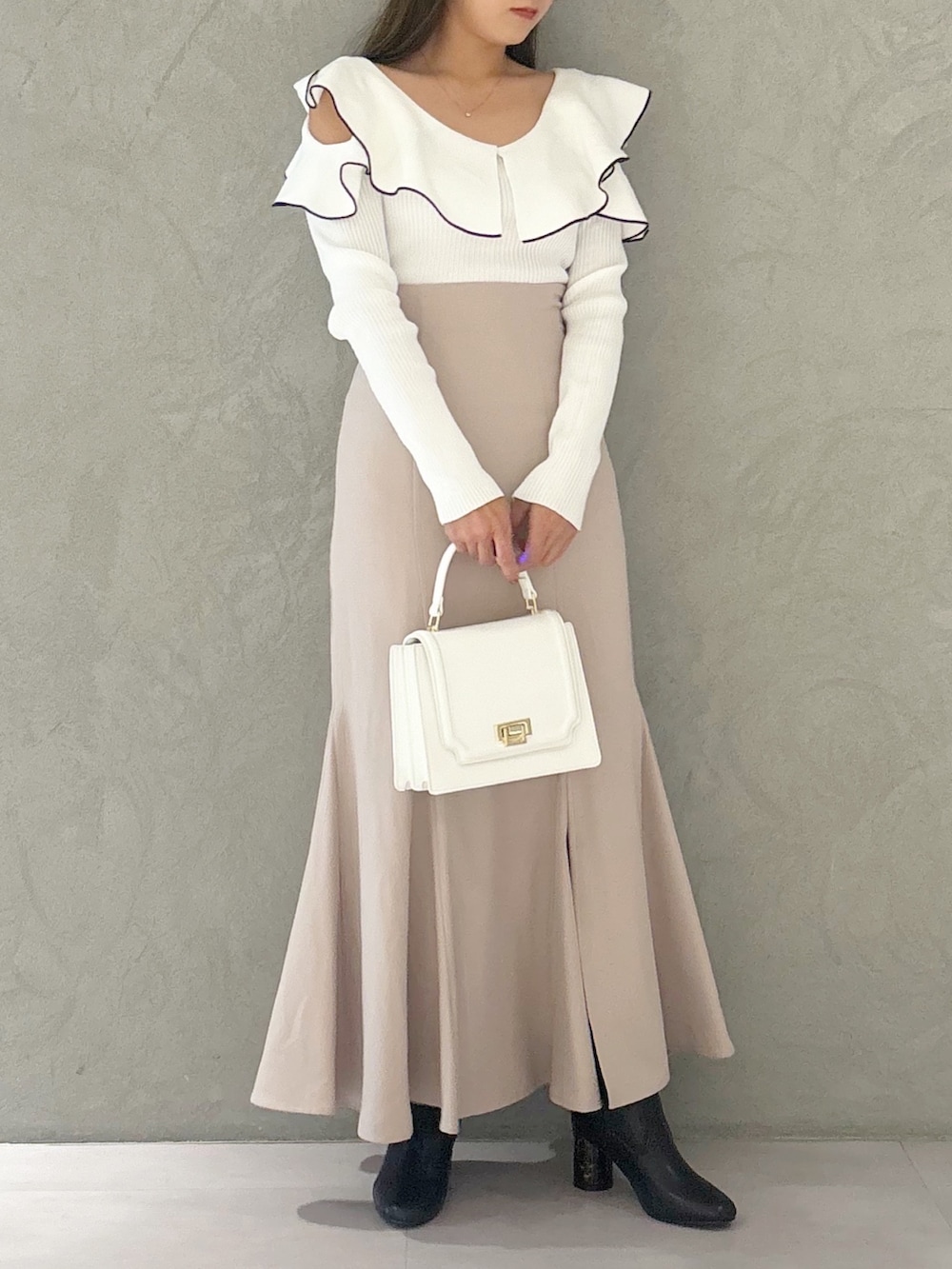 ピンク系のスカート、ブラック系のブーツ、ホワイト系のハンドバッグを着用したレディースの秋コーディネートの2枚目の写真