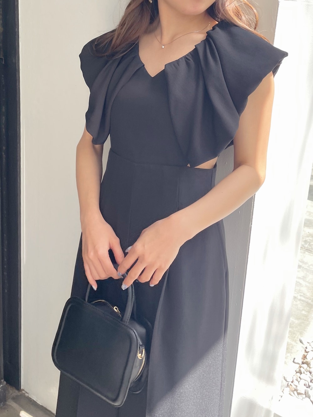 ブラック系のハンドバッグ、ブラック系のパンプス、ブラック系のつなぎ/オールインワンを着用したレディースの春コーディネートの2枚目の写真