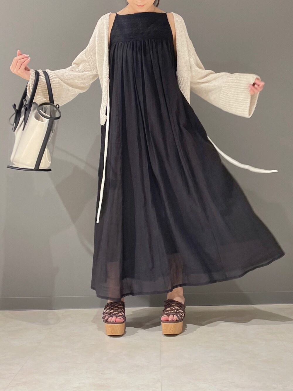 ブラック系のトートバッグ、ブラック系のワンピース、ブラウン系のサンダルを着用したレディースの春コーディネートの5枚目の写真