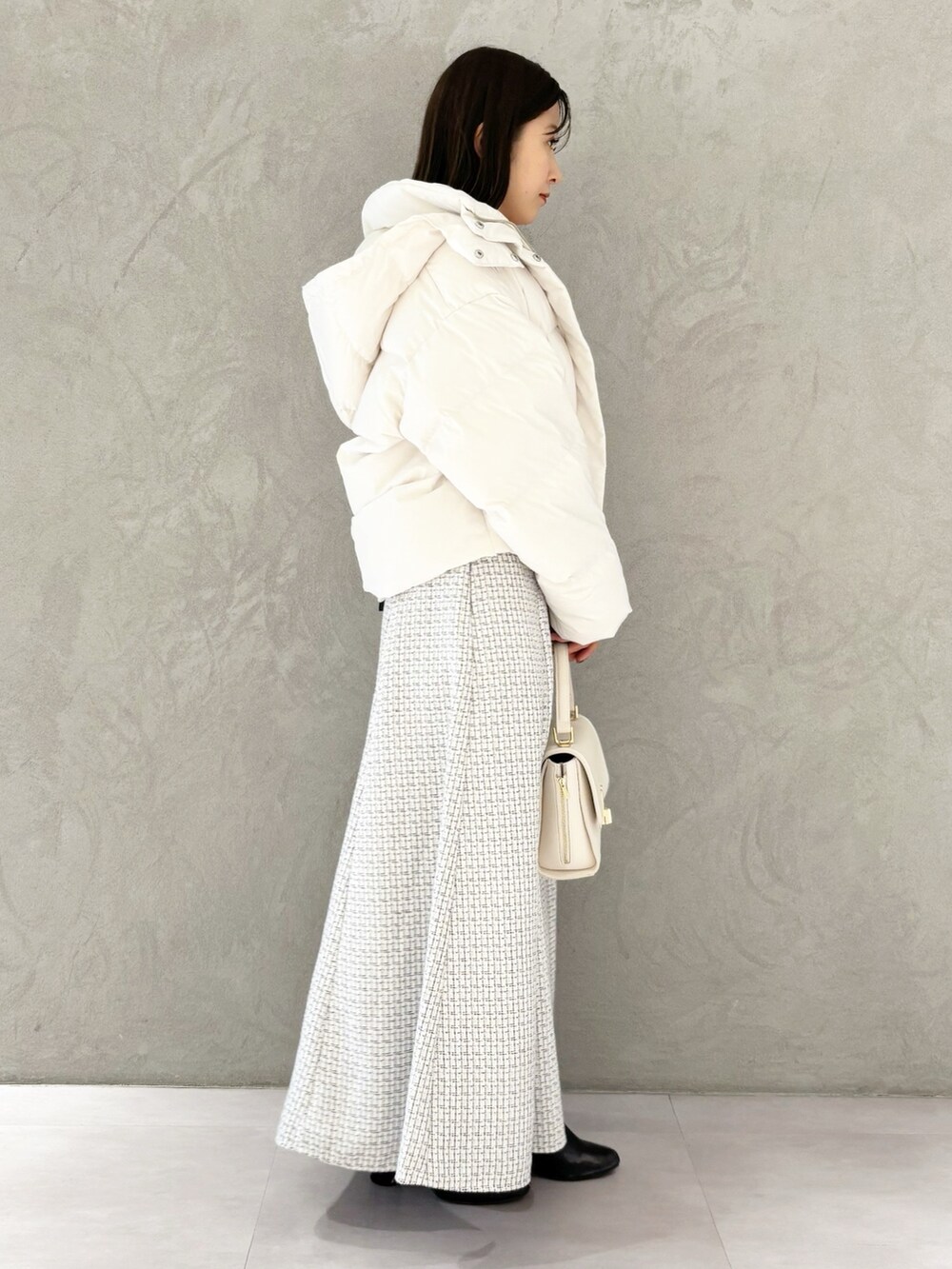 ホワイト系のスカート、ブラック系のブーツ、ホワイト系のハンドバッグを着用したレディースの冬コーディネートの6枚目の写真