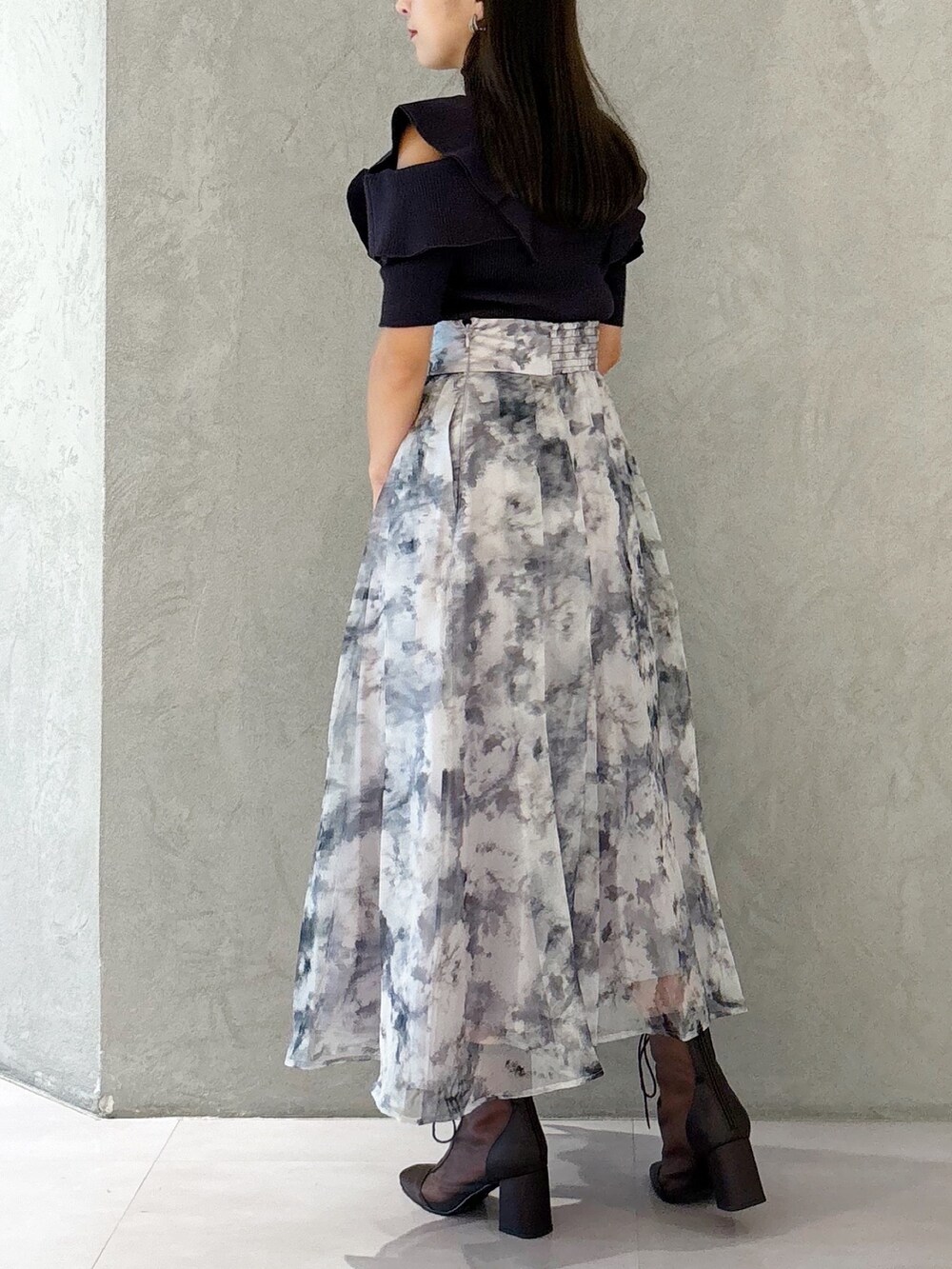 グレー系のスカート、ブラウン系のブーツ、ブラック系のショルダーバッグを着用したレディースの夏コーディネートの2枚目の写真