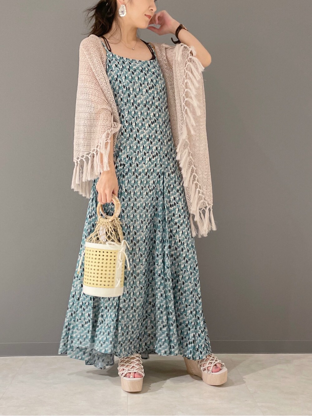 グリーン系のワンピース、ホワイト系のハンドバッグ、ホワイト系のサンダルを着用したレディースの春コーディネートの2枚目の写真