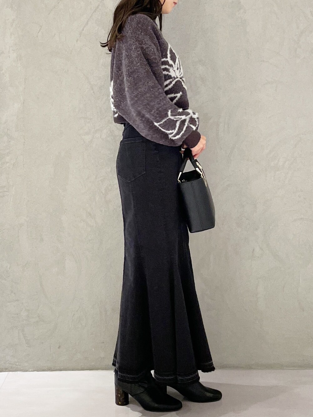 ブラック系のハンドバッグ、ブラック系のスカート、グレー系のニット/セーターを着用したレディースの秋コーディネートの4枚目の写真