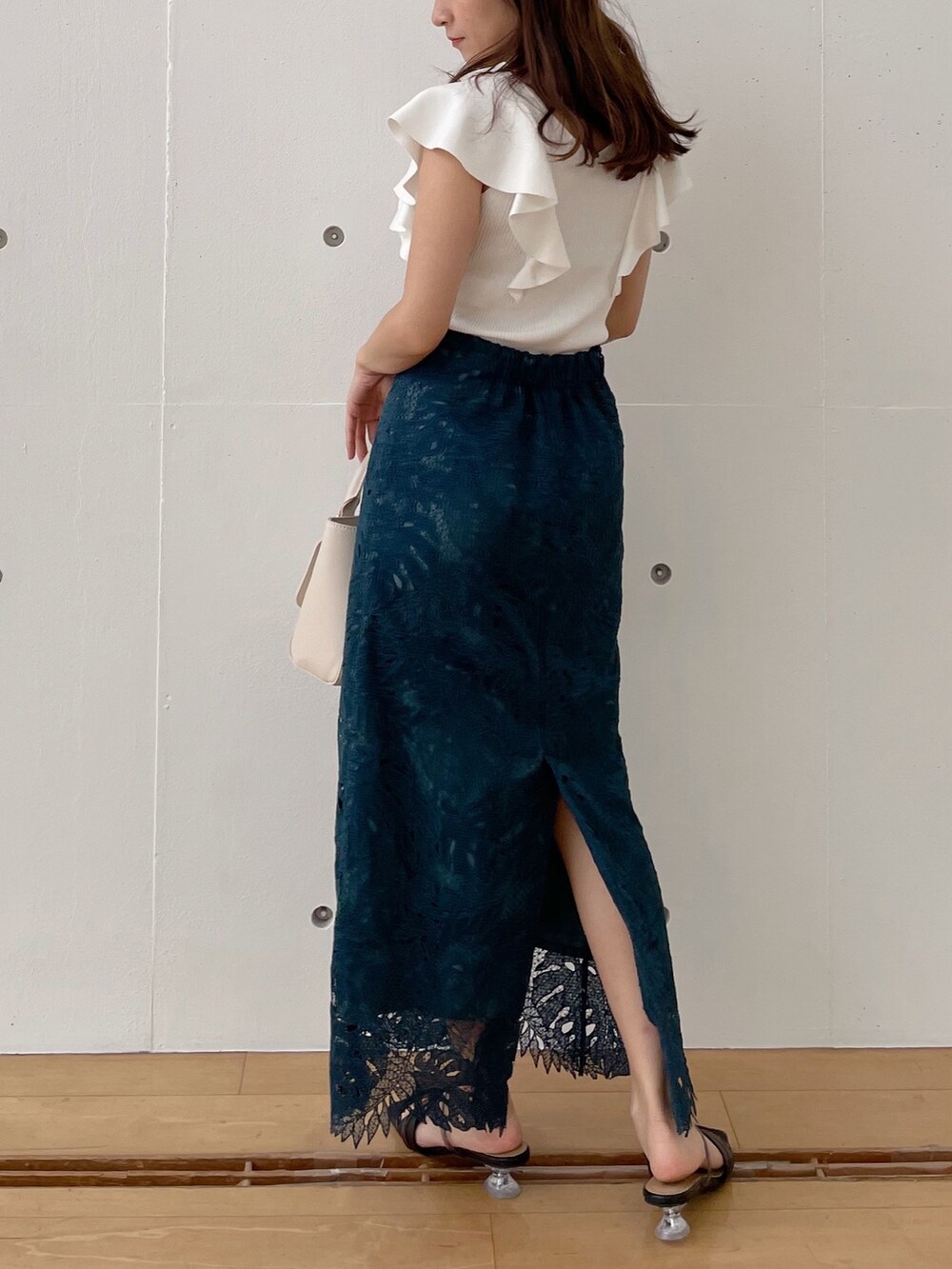 グリーン系のスカート、ブラック系のサンダル、ホワイト系のハンドバッグを着用したレディースの春コーディネートの5枚目の写真