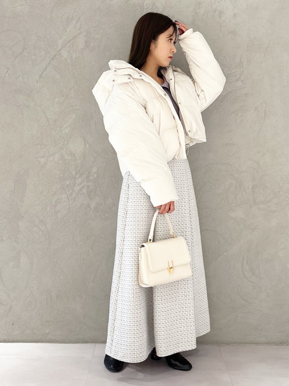 ホワイト系のスカート、ブラック系のブーツ、ホワイト系のハンドバッグを着用したレディースの冬コーディネートの2枚目の写真