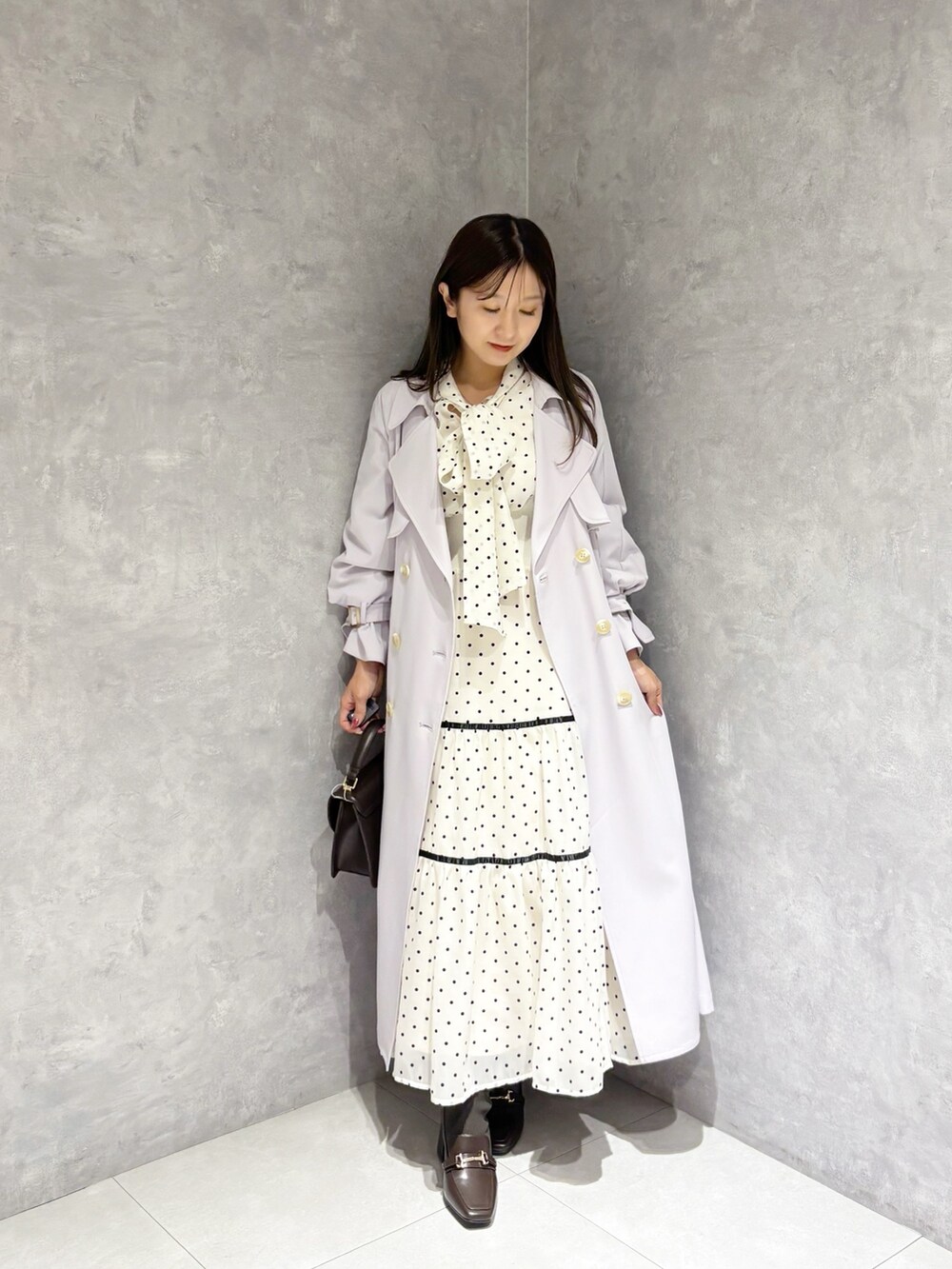 ホワイト系のワンピース、パープル系のトレンチコート、ブラウン系のハンドバッグを着用したレディースの冬コーディネートの9枚目の写真