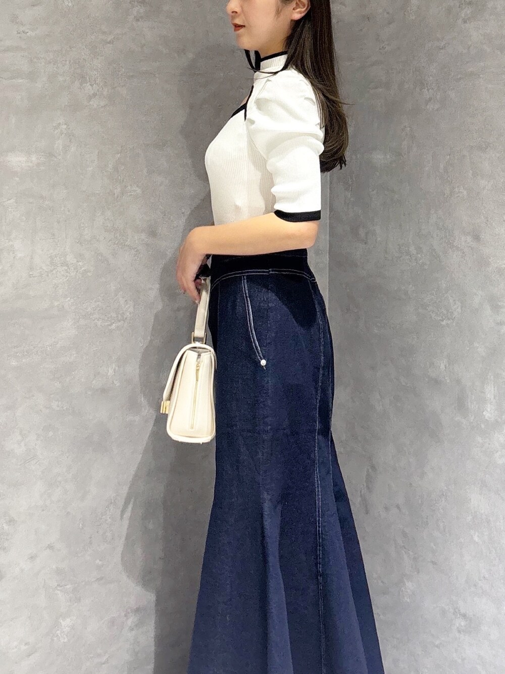 ブルー系のスカート、ホワイト系のパンプス、ホワイト系のハンドバッグを着用したレディースの春コーディネートの3枚目の写真