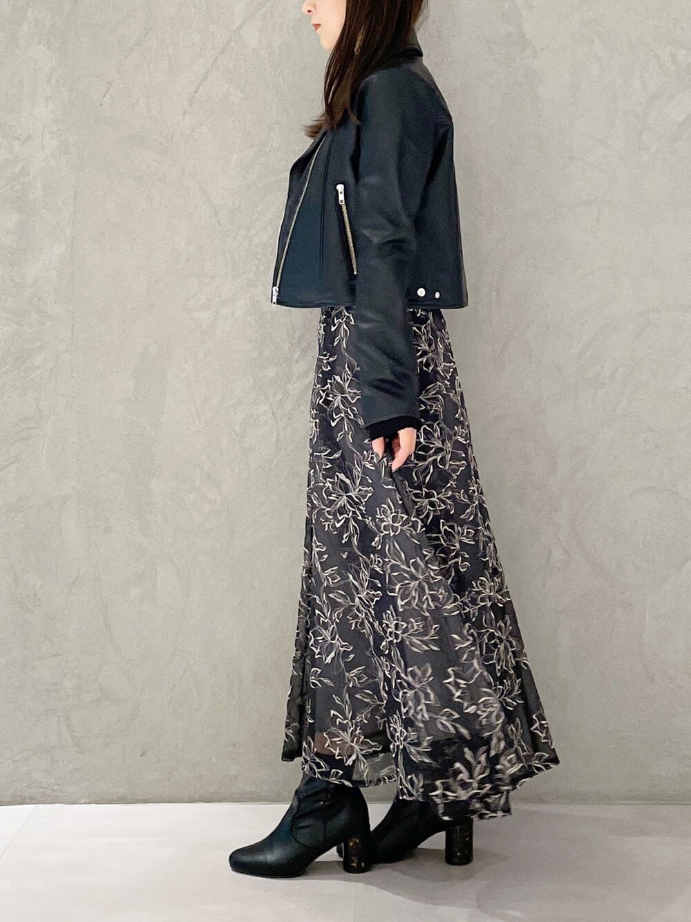 グレー系のスカート、ブラック系のライダースジャケット、ブラック系のブーツを着用したレディースの冬コーディネートの5枚目の写真