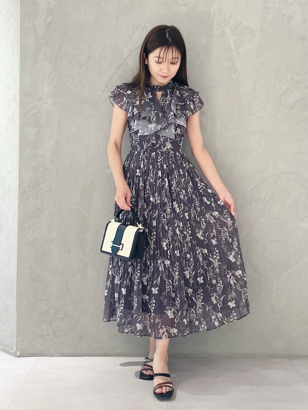 ブラック系のハンドバッグ、ブラック系のサンダル、グレー系のワンピースを着用したレディースの春コーディネートの6枚目の写真