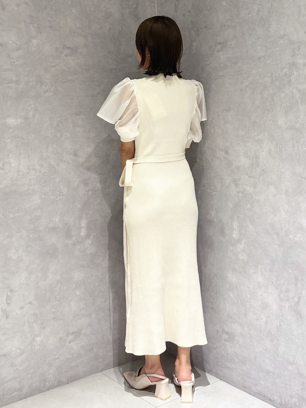 ホワイト系のワンピース、ホワイト系のパンプス、ブラウン系のハンドバッグを着用したレディースの春コーディネートの2枚目の写真