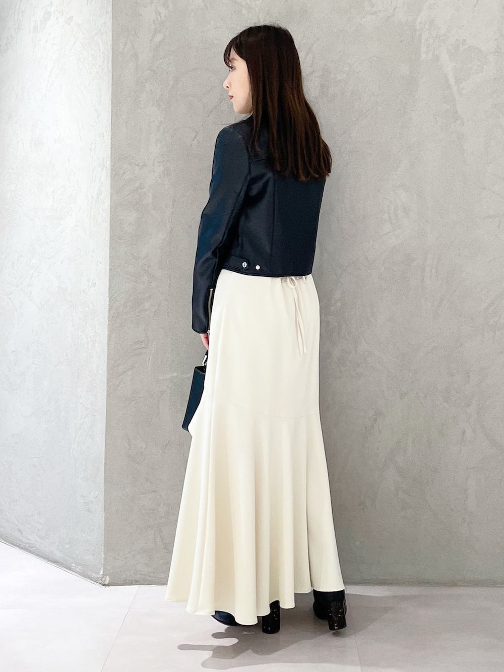 ブラック系のハンドバッグ、ブラック系のブーツ、ブラック系のライダースジャケットを着用したレディースの冬コーディネートの2枚目の写真