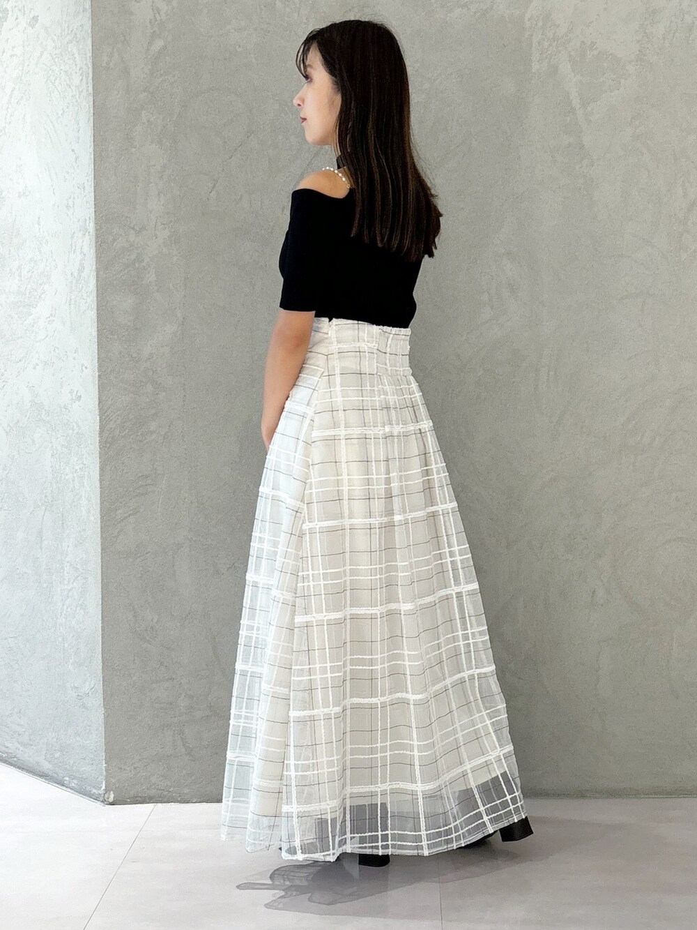 ホワイト系のスカート、ブラウン系のブーツ、ホワイト系のショルダーバッグを着用したレディースの秋コーディネートの2枚目の写真