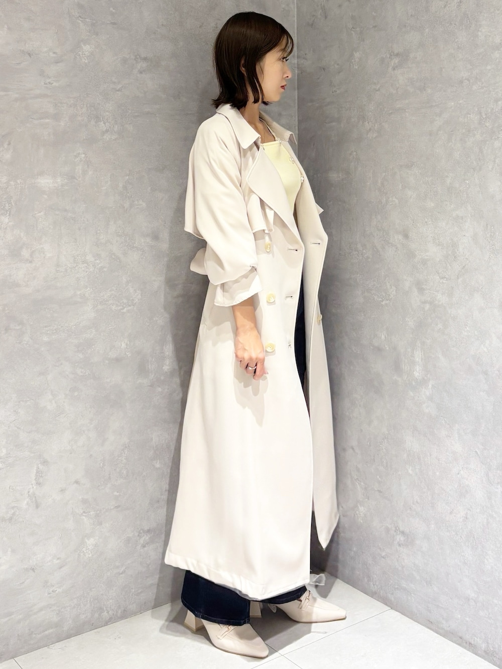 ブルー系のデニムパンツ、ホワイト系のパンプス、イエロー系のニット/セーターを着用したレディースの冬コーディネートの2枚目の写真