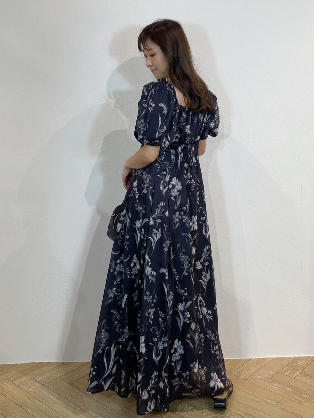 ブラック系のハンドバッグ、ブラック系のサンダル、グレー系のワンピースを着用したレディースの春コーディネートの5枚目の写真