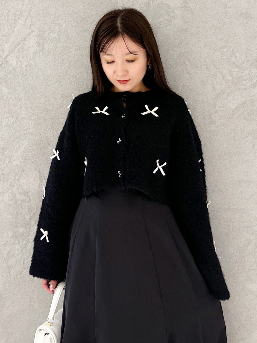 ブラック系のスカート、ブラック系のブーツ、ホワイト系のハンドバッグを着用したレディースの冬コーディネートの8枚目の写真