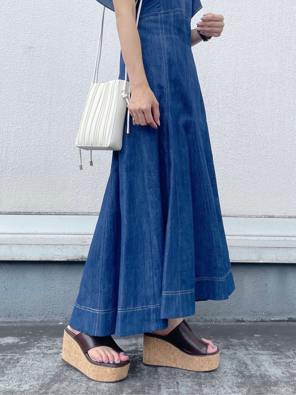 ブルー系のワンピース、ブラウン系のサンダル、ホワイト系のハンドバッグを着用したレディースの夏コーディネートの6枚目の写真